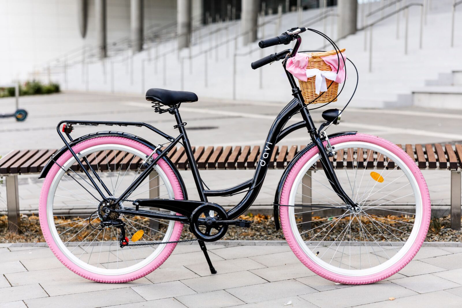 Cykel med korg och rosa däck utomhus.