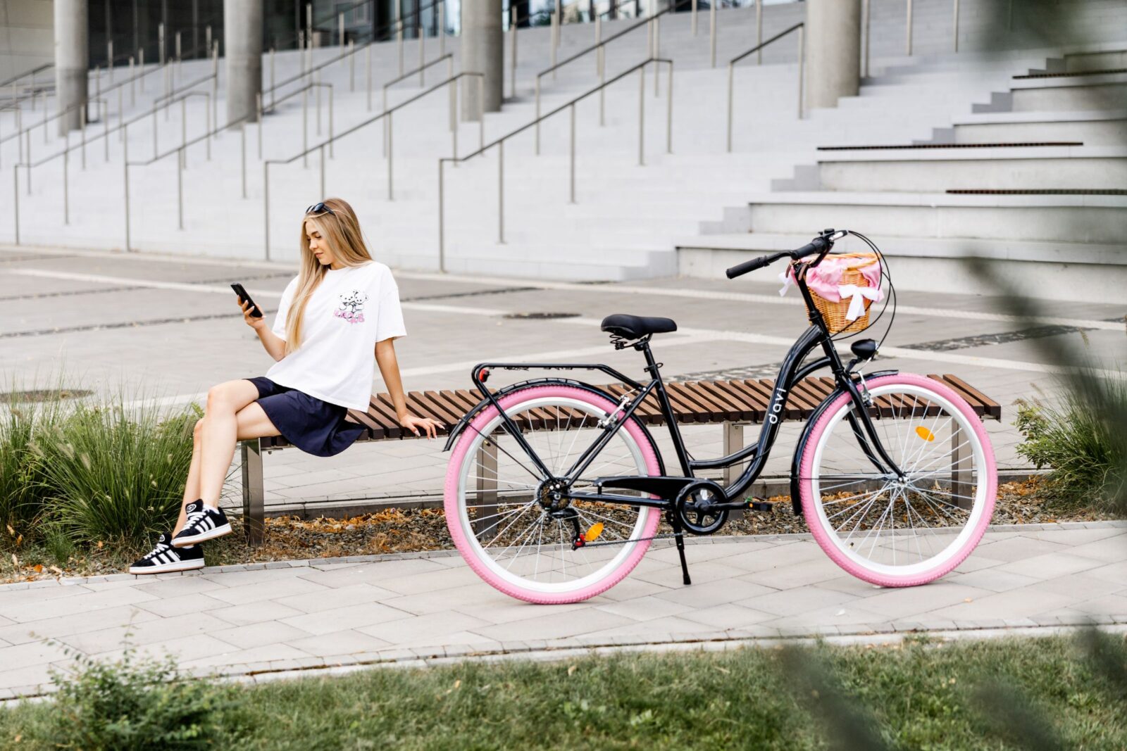 Kvinna på bänk med telefon och cykel nära.