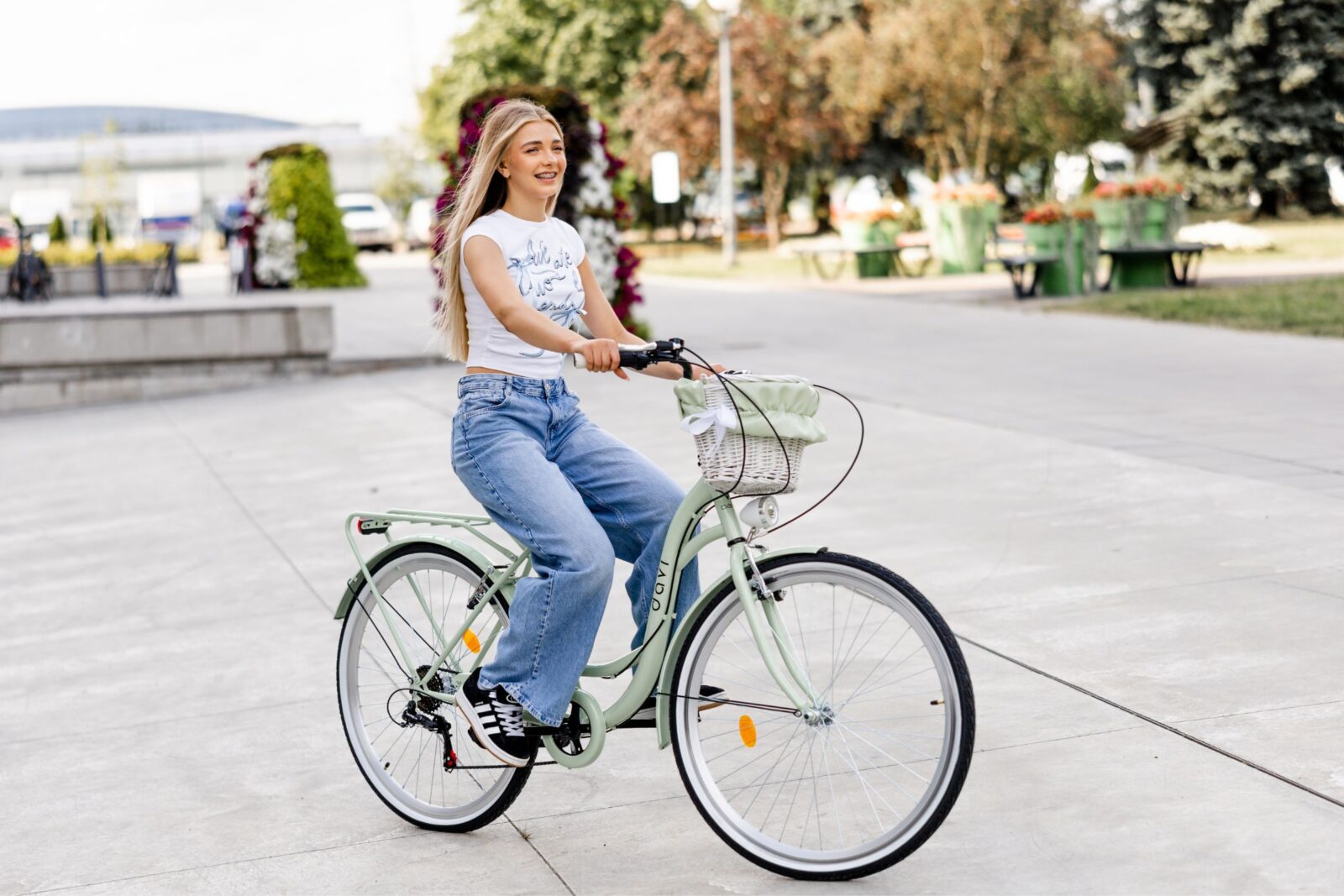 Leende kvinna cyklar i park med grön cykel.