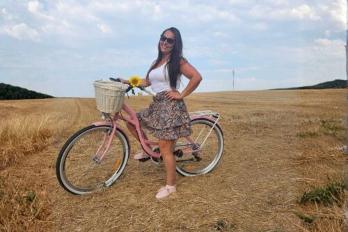 Kvinna med rosa cykel på fält med solros.