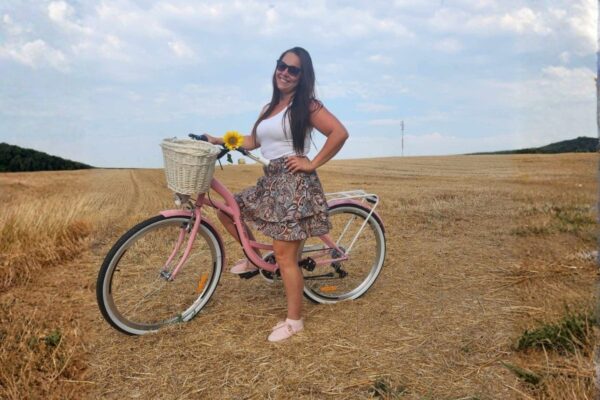 Kvinna med rosa cykel på fält med solros.